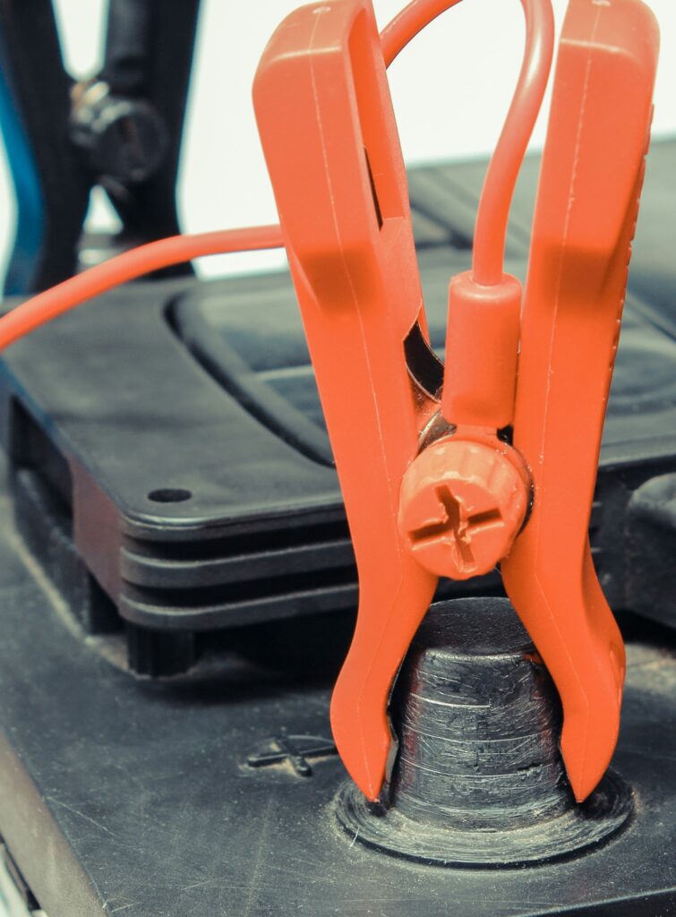 Car battery with clamps and connected cables of charger